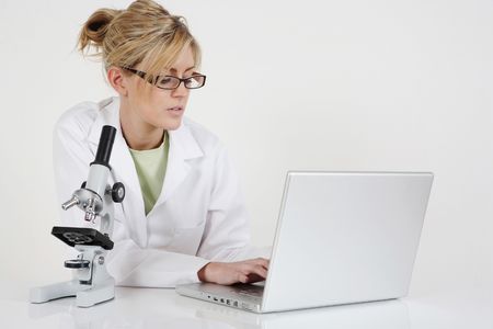 Woman in lab coat using laptopの写真素材