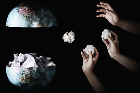 Human hand throwing crumpled paper into the center of globeの写真素材