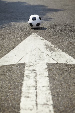 An arrow on the road pointing to soccer ballの写真素材