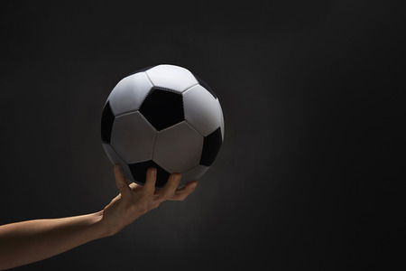 A hand holding a soccer ballの写真素材