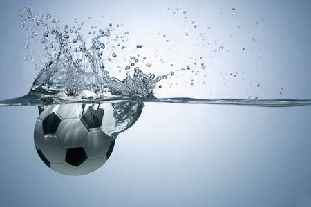 Soccer ball splashing into waterの写真素材
