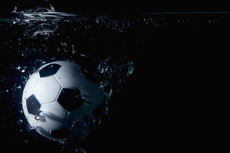 Soccer ball splashing into waterの写真素材