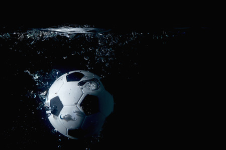 Soccer ball splashing into waterの写真素材