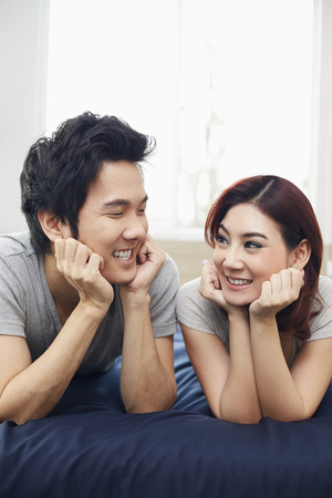 Couple lying on the bed, looking at each otherの写真素材