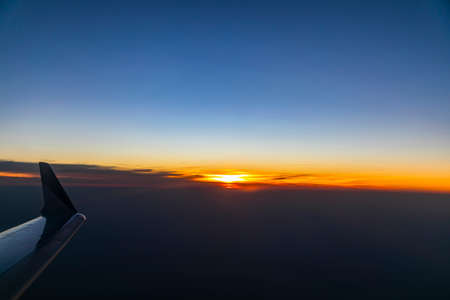 The sunset outside the airplane portholeの写真素材