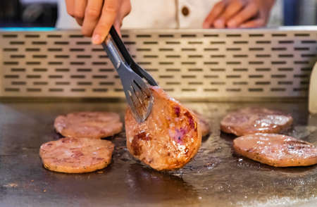 The cafeteria chef is flipping the steak
