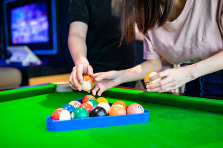 Female hands swinging a ball in front of a pool table