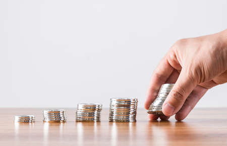 Pile of coins neatly arranged in front of businessman