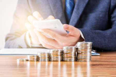 Pile of coins neatly arranged in front of businessman
