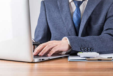 Pile of coins neatly arranged in front of businessmanの写真素材