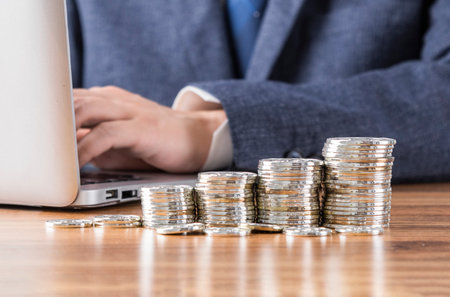 Pile of coins neatly arranged in front of businessmanの写真素材
