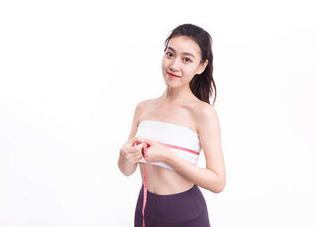 Attractive woman in white sports underwear is measuring her chestの写真素材