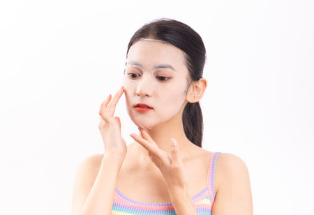 Young woman applying cream on her face isolated on a white background.の写真素材
