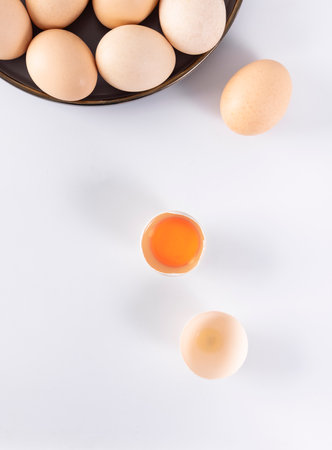 Eggs and egg yolk on white background, top view