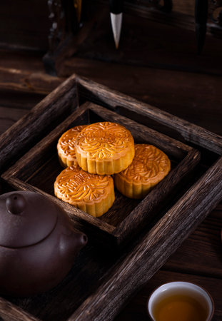 Moon cakes for Mid-Autumn Festival on wooden tray and teaの写真素材