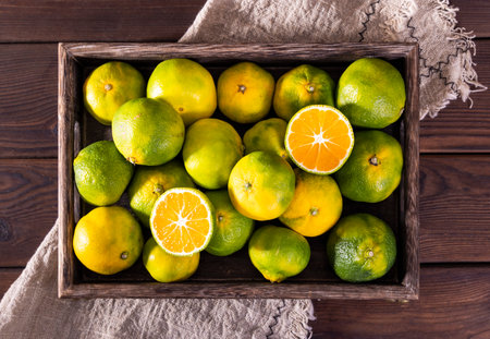Tangerines in a wooden box on a dark wooden background.の写真素材