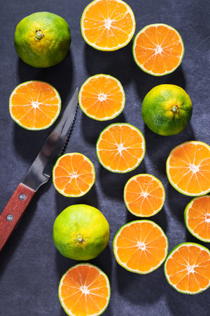 Slices of tangerines and a knife on a black backgroundの写真素材