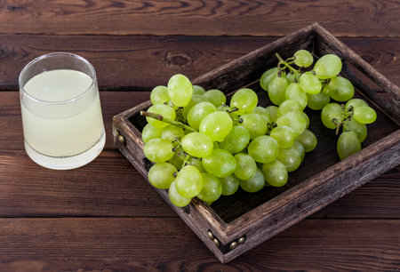 Grapes and a glass of grape juice on a wooden backgroundの写真素材