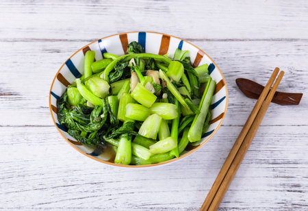 Stir-fried vegetables in bowl with chopsticks on wooden backgroundの写真素材