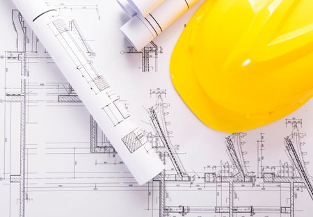 Architectural plans with yellow hard hat and rolled up blueprintsの写真素材