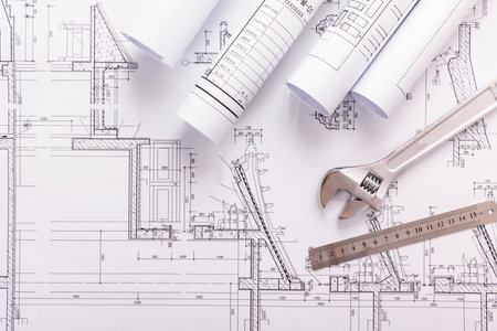 rolls of architectural drawings and tools on the background of technical drawingsの写真素材