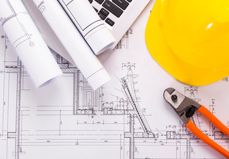 Yellow helmet, pliers and blueprints on a construction drawing.の写真素材