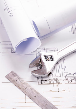 rolls of blueprints, adjustable wrench and ruler on construction drawingの写真素材