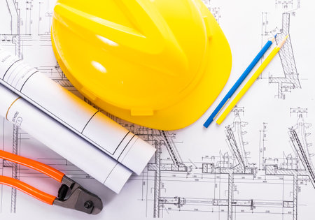 Yellow hardhat and blueprints with pencils isolated on white backgroundの写真素材