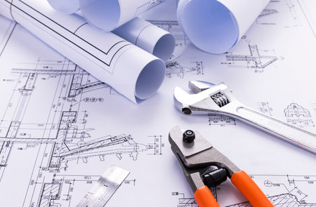 rolls of blueprints and adjustable wrench on a construction drawing of houseの写真素材