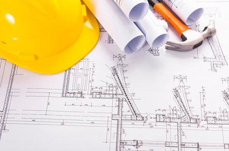 Architectural blueprints and yellow helmet on the desk of engineerの写真素材