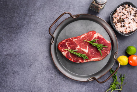 Raw beef steak with herbs and spices on dark background, top viewの写真素材