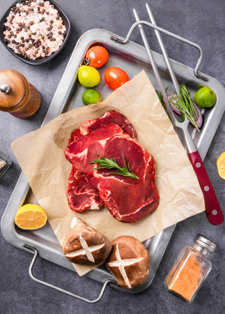 Raw beef steak with ingredients for cooking on a baking sheet, top viewの写真素材