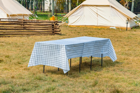 Camping table and chairs on the grass in front of a tentの写真素材