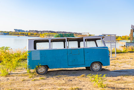 Old blue camper van on the shore of a lake in autumnの写真素材