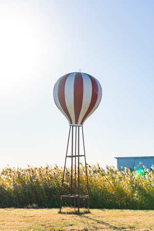 Red and white hot air balloon in the field with blue sky backgroundの写真素材