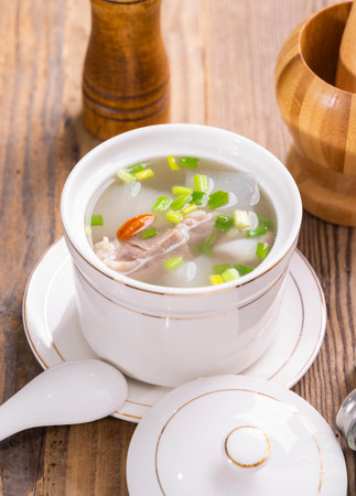 Chinese soup with pork and vegetables in a bowl on a wooden tableの写真素材