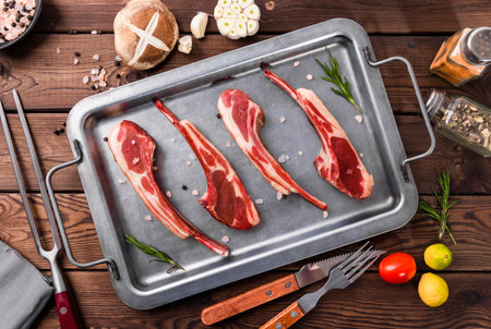Raw lamb chops on a baking sheet. On a wooden background.の写真素材