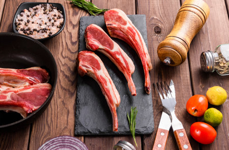 Raw lamb chops with ingredients for cooking on wooden background. Top viewの写真素材