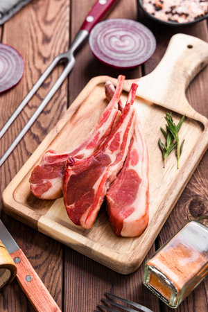 Raw lamb chops on a cutting board. On a wooden background.の写真素材