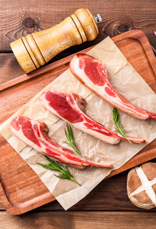 Raw lamb chops on a cutting board with rosemary and spices.の写真素材