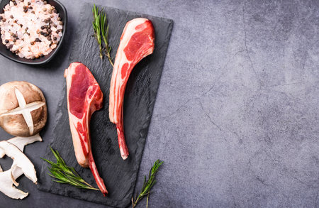 Raw lamb chops with ingredients on stone cutting board. Top view with copy spaceの写真素材