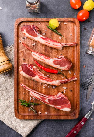 Raw lamb chops with spices and herbs on wooden cutting board. Top viewの写真素材