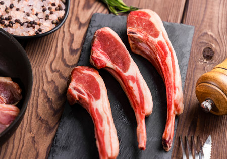 Raw lamb chops on cutting board with salt and pepper on wooden backgroundの写真素材