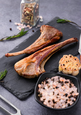 Grilled lamb chops with spices and herbs on black slate plate.の写真素材