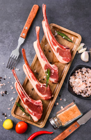 Raw lamb chops with spices and herbs as top view on a wooden boardの写真素材
