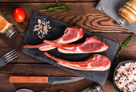 Raw lamb chops with spices and herbs on wooden background. Top viewの写真素材