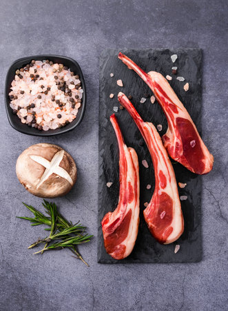 Raw lamb chops with ingredients for cooking on a stone board, top viewの写真素材
