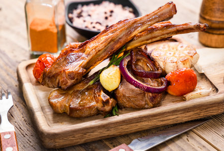 Grilled lamb chops with vegetables on a wooden board, close upの写真素材