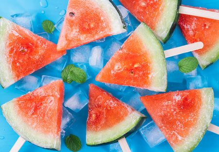Watermelon slices with ice cubes on blue background. Top view.の写真素材