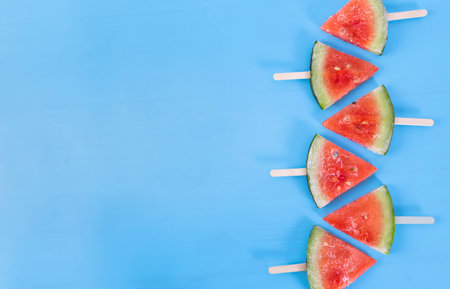 Slices of watermelon on a stick on a blue backgroundの写真素材